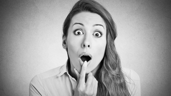 Bild zeigt junge Frau mit rotem Haar und erschrockenem Gesichtsausdruck.